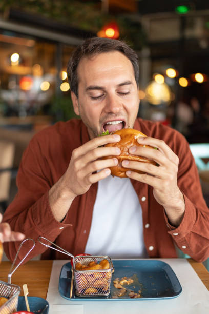 istock Young man enjoying in eating hamburger in a pub. 2196989385
