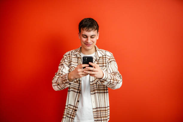 istock young man use mobile phone stand in front red background studio shot 2196991401