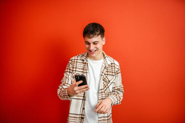 istock young man use mobile phone stand in front red background studio shot 2196991650