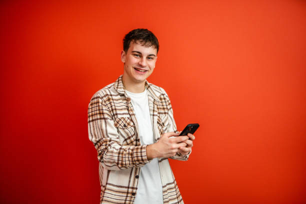 istock young man use mobile phone stand in front red background studio shot 2196991674