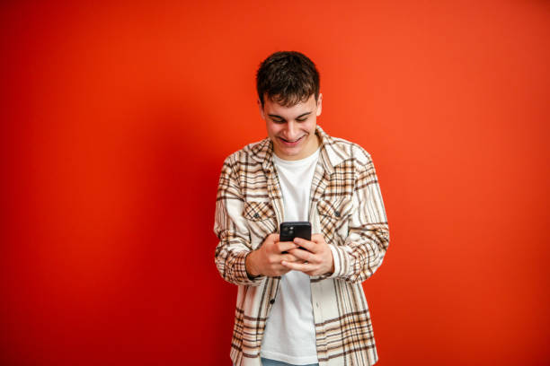 istock young man use mobile phone stand in front red background studio shot 2196991680