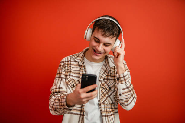 istock young boy with headphones studio shot on red background use cellphone 2196991836