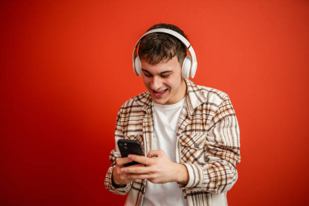 istock young boy with headphones studio shot on red background use cellphone 2196991931