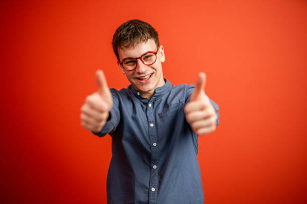 portrait of young man stand and thumb up in front red background studio shot