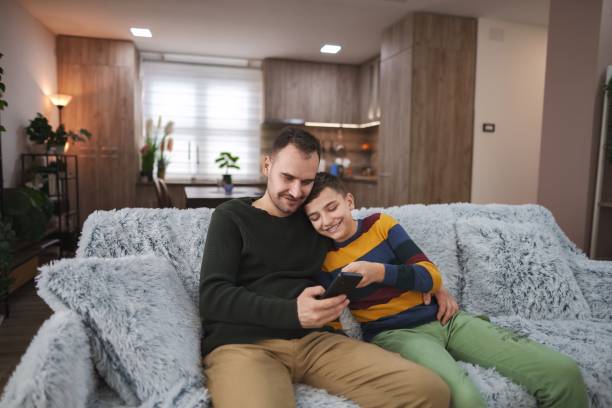 istock Father and son sharing a moment of joy while using a smartphone on the sofa 2196993576