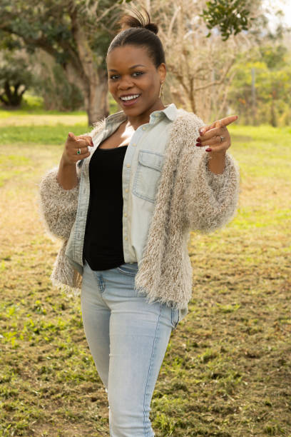 istock Black woman smiling and pointing with both hands outdoors 2196994959