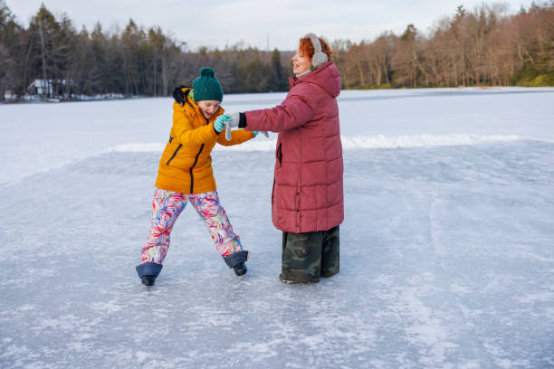 istock Daughter takes first steps on frozen lake surface. Redhead mother steadies her elementary-aged girl during winter skating lesson in Poconos 2197000507