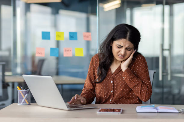 istock Woman in office dealing with ear pain while working on her laptop 2197013392