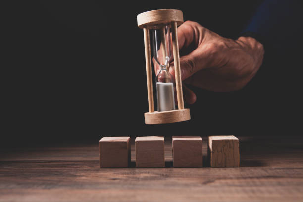 istock hourglass with hand on a dark background 2197013438
