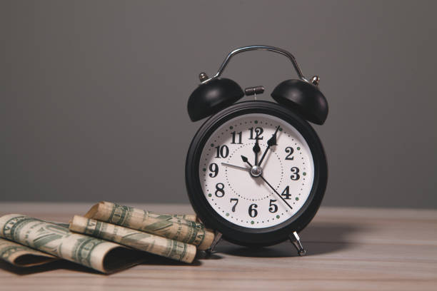istock clock with money and dollar banknotes. time is money concept. 2197013463
