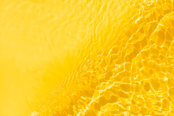 istock Gold water with ripples on the surface. Defocus blurred transparent orange colored clear calm water surface texture with splashes and bubbles. Water waves with shining pattern texture background. 2197014556