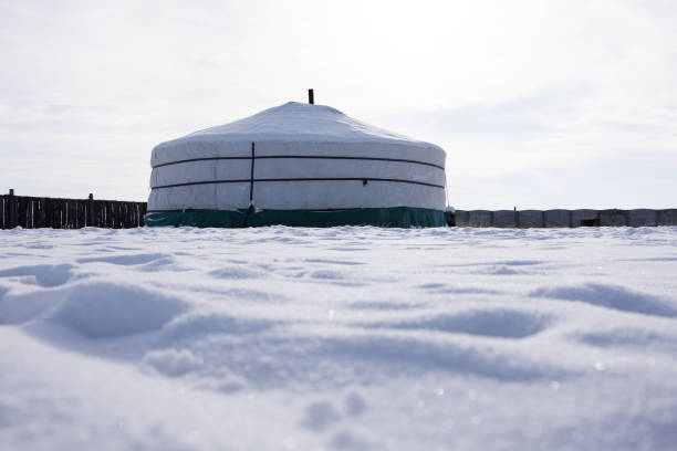 A traditional Mongolian yurt stands in a vast snow-covered landscape under a bright winter sky. The scene highlights the nomadic lifestyle, resilience, and cultural heritage of Mongolia in harsh conditions.