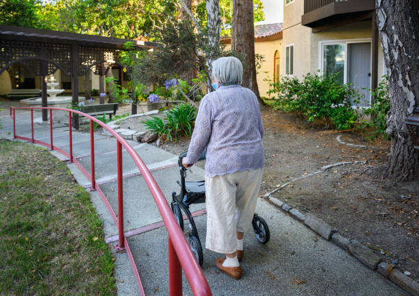 Elderly woman walking outdoors using a mobility walker in a retirement village.