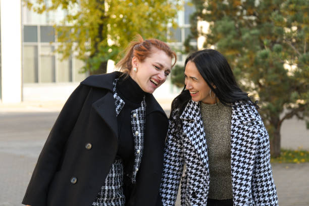 istock Women share a joyful moment walking down a tree-lined street in autumn 2197033913