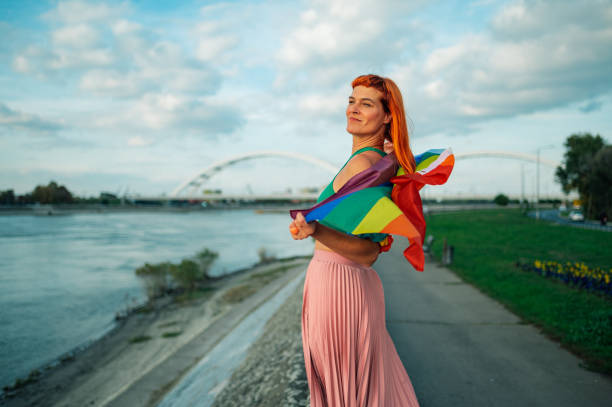 istock Woman holding rainbow flag by river with bridge 2197042467