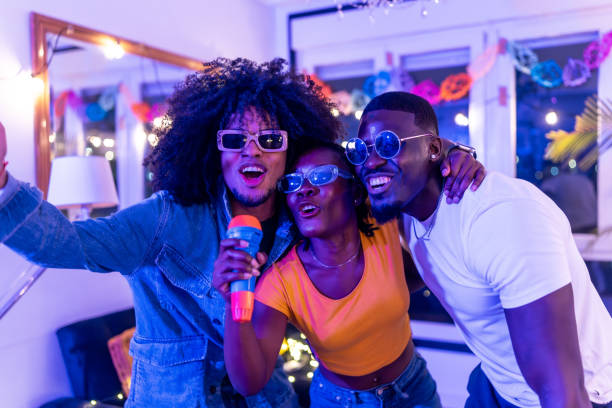 Three young friends singing karaoke together at home party