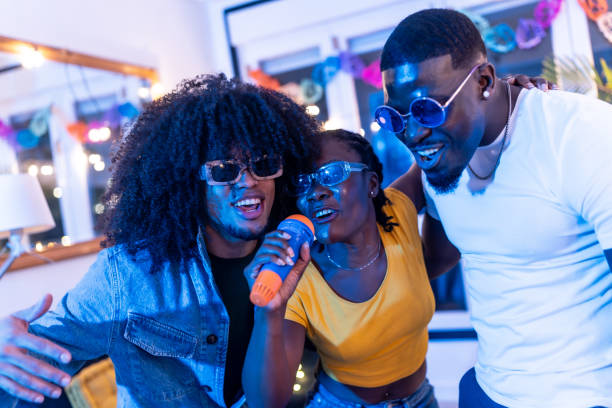 istock Friends singing karaoke with wireless microphone at home party 2197044420