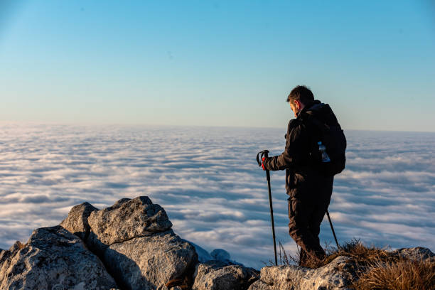 istock Hiker Standing on Mountain Summit Overlooking a Sea of Clouds 2197045847