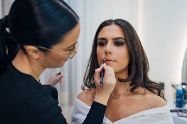 istock A concentrated make-up artist lines her client's lips using a lip liner, wanting to achieve the effect of enlarged lips. The concept of professional make-up 2197046432