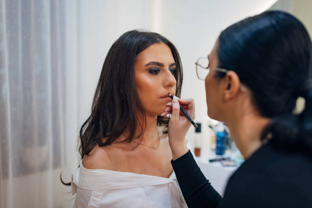 istock A concentrated professional make-up artist lines her client's lips using a lip liner, wanting to achieve the effect of enlarged lips. The concept of professional make-up 2197046439