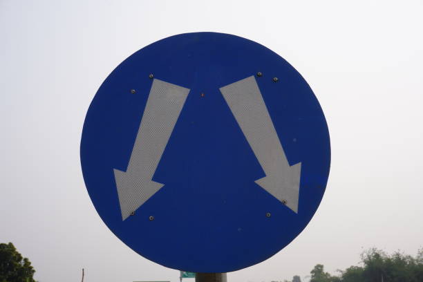 istock The blue sign with two white arrows indicates a divergence in the road ahead which means that traffic is permitted to pass on either side of an upcoming island or obstruction in the road. 2197047902