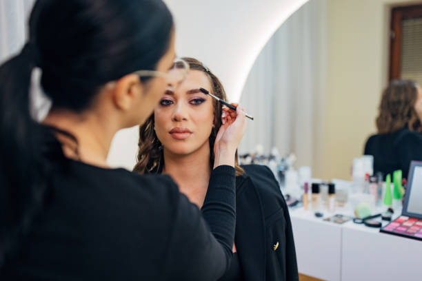 istock A focused make-up artist outlines her client's eyebrows with a brush and then combs them 2197048147