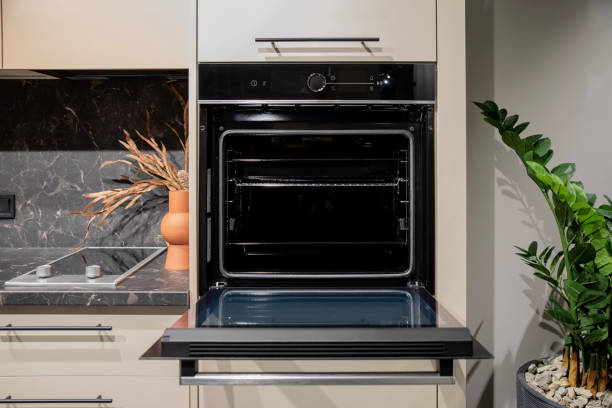 istock Black built-in oven with open door and visible cooking racks 2197048908