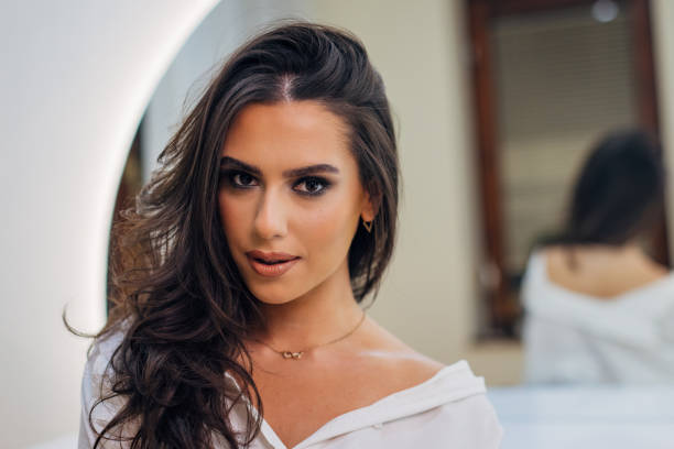 Portrait of a beautiful woman with side-swept hair standing in a beauty studio after completing a professional make-up treatment