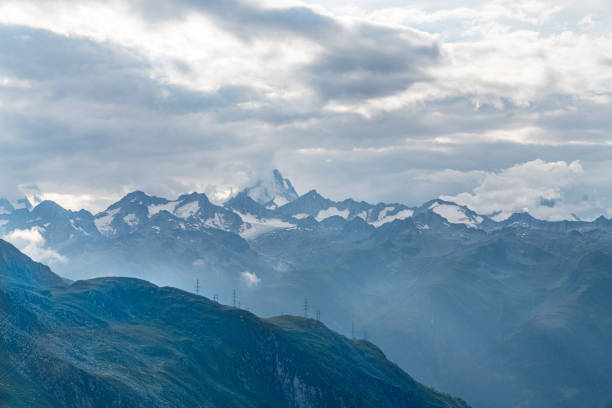 A mountain range in Swiss Alps with snow on the peaks. The sky is cloudy and the mountains are in the distance