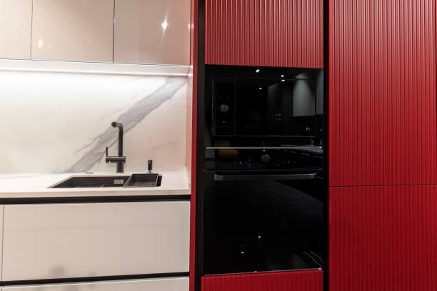 istock Modern red kitchen with black electric oven, microwave  and faucet 2197055719
