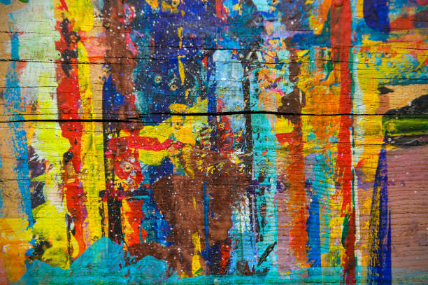 Close-up of vibrant watercolor pans in deep blue, purple, and orange tones. The paint surface is splattered with dried pigment, highlighting artistic use and dynamic contrast.