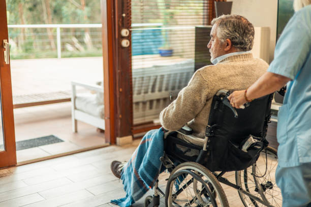 istock Nurse pushing elderly man in wheelchair at home 2197056587