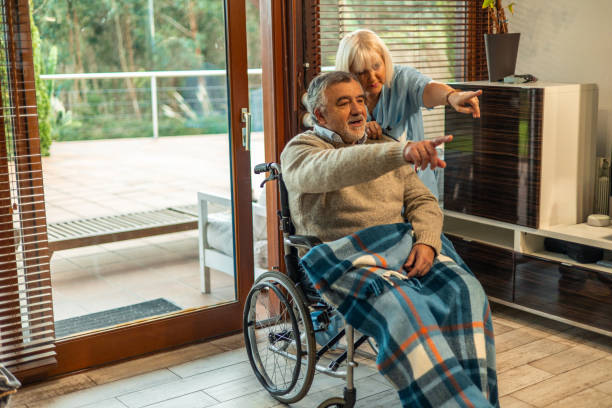 istock Nurse assisting elderly man in wheelchair pointing at something 2197056591