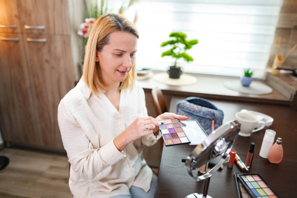 istock Woman doing her makeup choosing eyeshadow from a palette sitting at home 2197056804