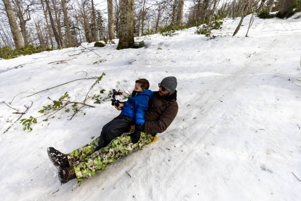 istock Cheerful father and son sledding on snow 2197057392