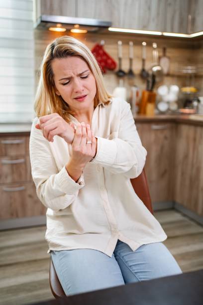 istock Woman suffering from wrist pain while sitting in the kitchen 2197060229