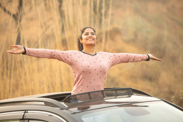 istock Woman enjoying road trip while looking through sun roof 2197063287