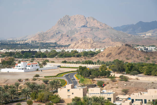 : A scenic view of small traditional houses resting beneath the rugged Hatta Mountains in Dubai, showcasing the contrast between nature and rural architecture
