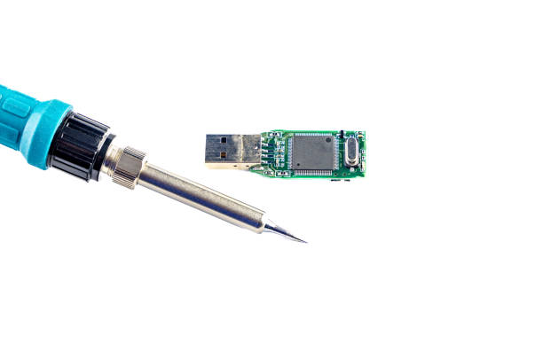 Soldering iron in the hands of a man who repairs a damaged flash drive, on a white background