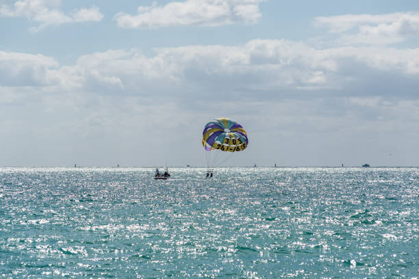 Colorful parasail wing pulled by a boat in the sea water Miami, FL, USA - March 30, 2024: Parasailing over the Atlantic Ocean in Miami Beach, Florida, USA. miami parachuting stock pictures, royalty-free photos & images