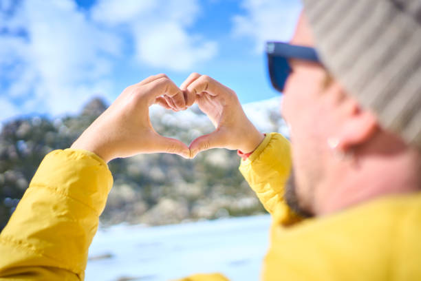 Man making heart shape with hands in winter landscape