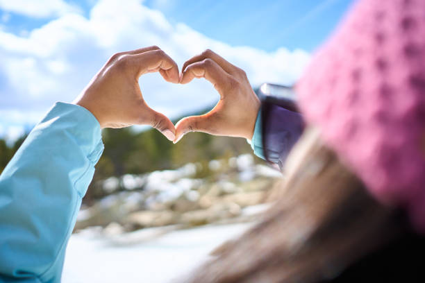 istock Woman making heart shape with hands in winter landscape 2197076788