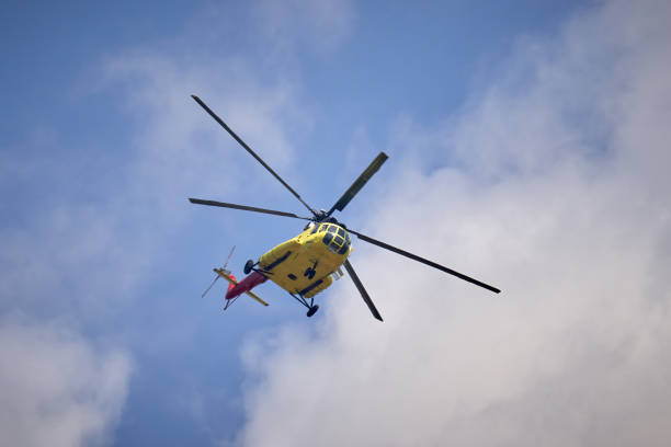 A yellow and red helicopter soars through a scenic sky filled with soft clouds, evoking advancement and exploration in air travel.
