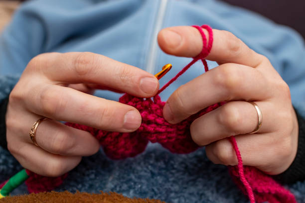 istock Woman hands knitting with a crochet hook and red thread , soft focus close up 2197078962
