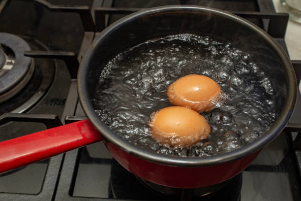 istock Two orange eggs boiling in a  black pot with bubbles and steam, soft focus  close up 2197079268