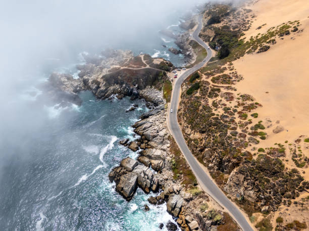 istock Aerial View: Coastal Highway Overlooking Rocky Shoreline and Misty Ocean 2197081777