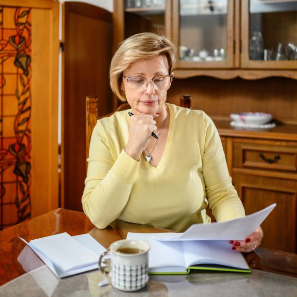 istock Mature woman checking finances and drinking tea at home 2197084911