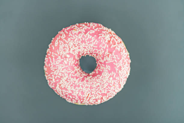 istock A round, pink-glazed doughnut with decorative toppings is shown against a plain backdrop 2197088160