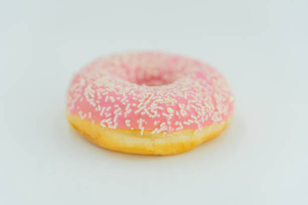 istock A single golden-brown doughnut with pink icing and white sprinkles is shown against a plain background The photograph has high contrast lighting 2197088287