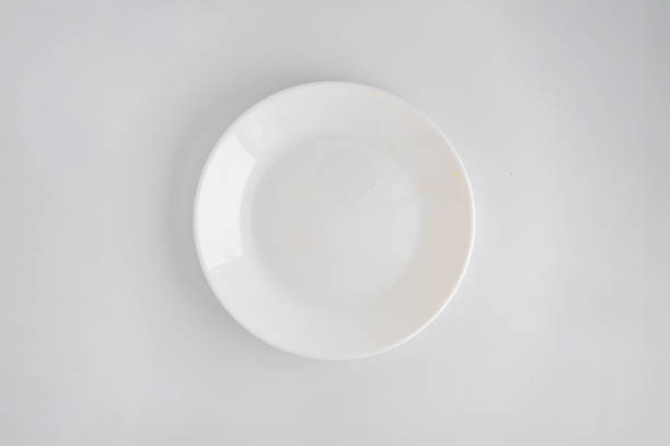 istock A white plate with food remnants on one side, positioned against a blurred tabletop background 2197088375